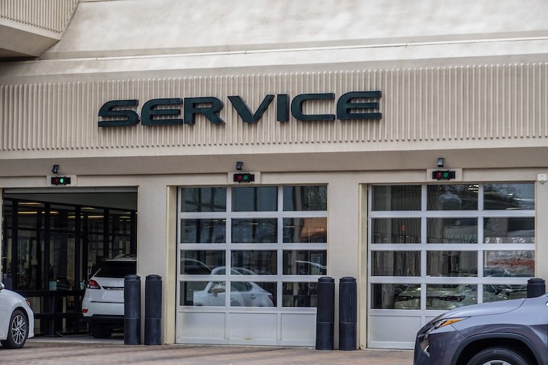 White cars entering an automobile service center garage through an open garage door. Two other doors are closed dealership service center alternative in Boise
