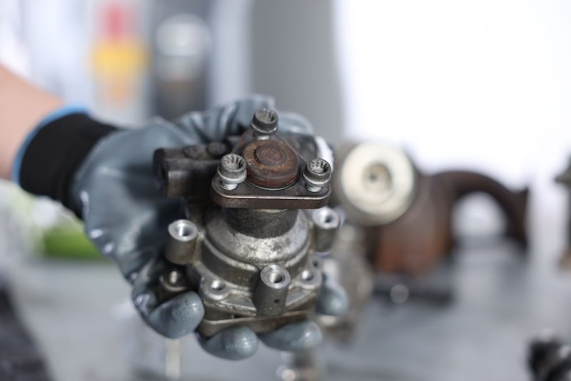 Auto part. Professional mechanic with power steering pump indoors, closeup. Space for text