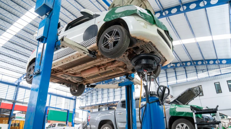 Car lifted on hydraulic hoist in auto repair shop