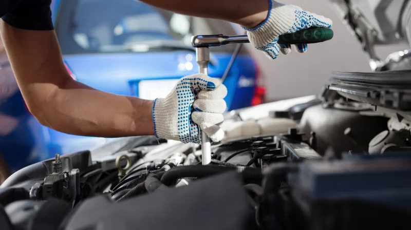 Mechanic using ratchet to repair car engine