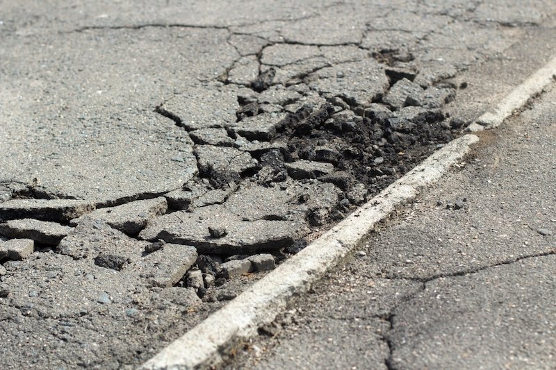 Broken asphalt. It's a bad road. Pits on the road in Russia. Spoiled road surface.